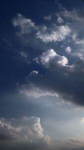 Vertical shot of a dramatic sky with cumulus clouds and deep blue hues at dusk.