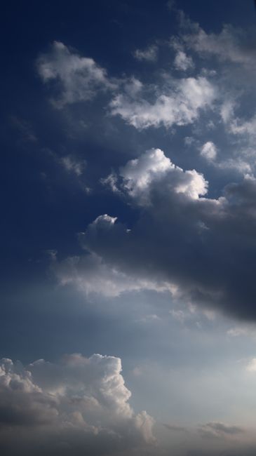 Vertical shot of a dramatic sky with cumulus clouds and deep blue hues at dusk.
